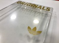 Lettrage doré brillant apposé sur coffret en plexiglas pour Adidas
